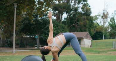 woman in white tank top and gray leggings doing push up on black exercise ball on near near near near