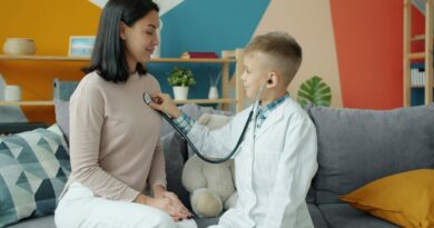 Boy in doctor's coat listens to mother's chest